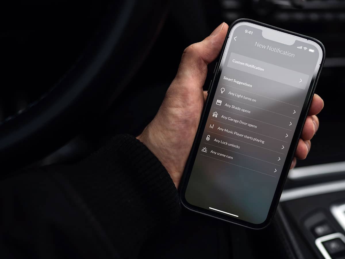 Person holding smartphone with smart home app open.