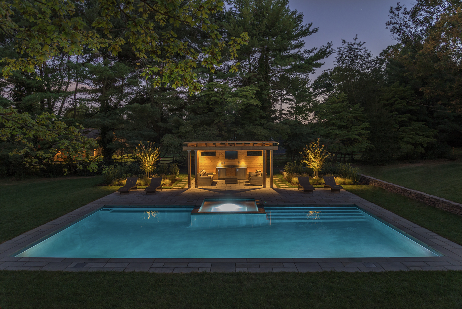 Illuminated pool and patio under evening sky